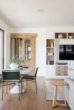 a living room filled with furniture and a flat screen tv mounted on a wall next to a window