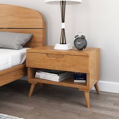 a nightstand with a lamp on top of it next to a bed and a night stand