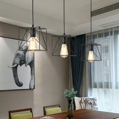 a dining room table and chairs with an elephant painting on the wall in the background