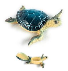 two small turtle figurines sitting next to each other on top of a white surface