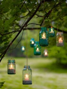 mason jars filled with candles hanging from a tree