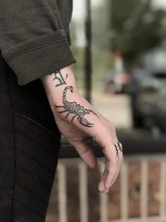 a man's hand with a scorpion tattoo on his left wrist and the other arm