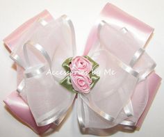 a close up of a pink flower on a white surface with ribbon around the center