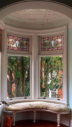 a window seat in the corner of a room with wood floors and stained glass windows