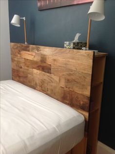 a bed with a wooden headboard and night stand in the corner next to it