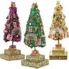 three small christmas trees in different colors and designs, each with a fan on top