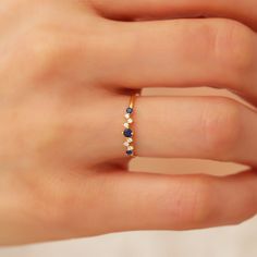 a woman's hand wearing a gold ring with blue and white stones