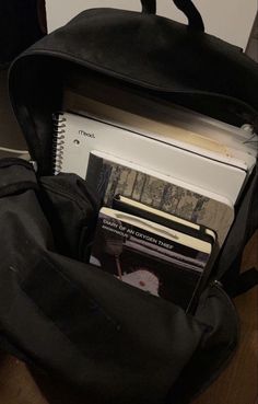 an open black backpack sitting on top of a wooden floor