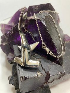 a piece of jewelry sitting on top of a purple rock next to a chain necklace