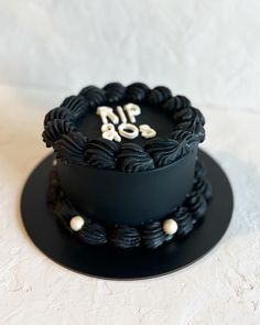 there is a black cake with white letters on the top and bottom, sitting on a plate