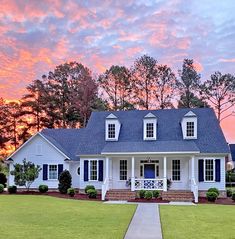 a white house with blue shutters on the front and side windows at sunset in virginia