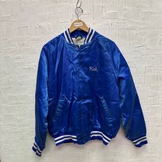 Vintage Hilton Active Apparel Blue Silky Bomber Jacket | Vintage Bomber Jacket | Blue Silky Bomber Jacket | Size XL | SKU NPW-1253 | Used - Stain on upper middle front, right pocket, right upper sleeve. Wear and tear on middle front. Scratches on lower right sleeve and left sleeve. Loose threads on back embroidery. Scratches on back.  XL Size for Men, Please refer to photos for measurements Chest 27" Length 28" We only ship to the US and Canada. All our items of vintage condition. Most of the it Blue Spring Outerwear For College, Retro Blue Hooded Varsity Jacket, Blue Retro Hooded Varsity Jacket, Blue Hooded Retro Varsity Jacket, Vintage Blue Outerwear For College, Back Embroidery, Active Outfits, Jacket Vintage, Favorite Outfit