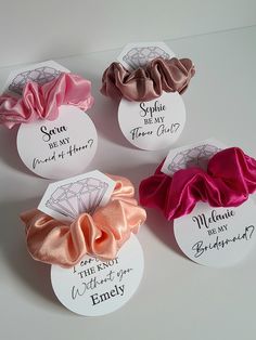 four different colored scrunffle hair clips with names on the back and one has a diamond in it