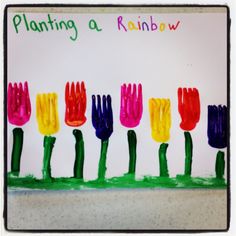 an art project with handprinted flowers and writing on the paper that says planting a rainbow