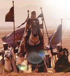 a group of men riding on the backs of horses next to each other in front of flags