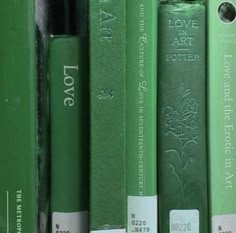 several green books are lined up on a shelf