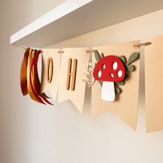 a paper banner that says ohoh hanging on a wall with ribbon and mushrooms attached to it