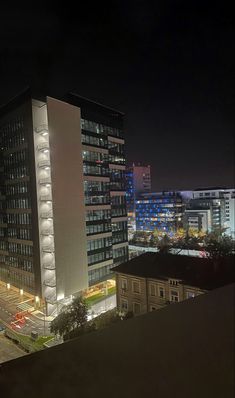 the city is lit up at night with lights on and buildings in the foreground