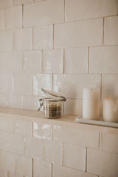 a candle is sitting on top of a shelf next to a white brick wall in a bathroom