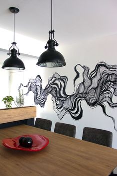 a wooden table topped with a red plate covered in black food next to two hanging lights