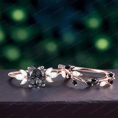 two rings with black and white stones on them sitting on top of a wooden table