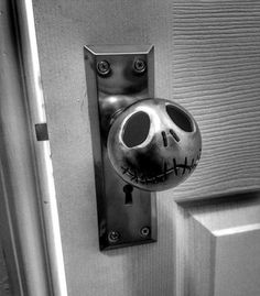 a black and white photo of a door handle with a skeleton face on the front