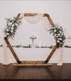 a wedding arch with flowers and greenery on the floor in front of a white wall