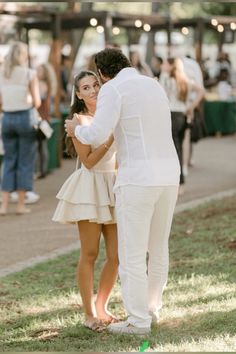 a man and woman standing next to each other in the grass