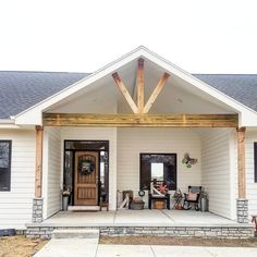 the front entrance of a white house with wood beams on it's roof and porch