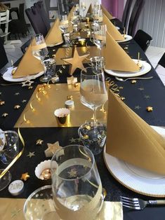 a long table is set with gold and white plates, silverware, and champagne glasses