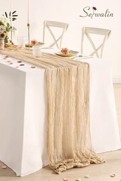 the table is set with two white chairs and a long beige scarf draped over it