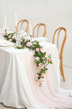 the table is set with pink roses and greenery for an elegant wedding breakfast or bridal party