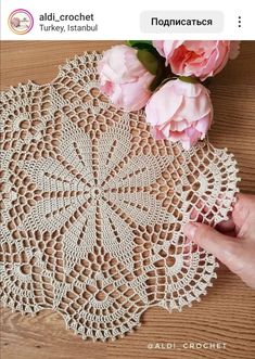 an image of a crocheted doily with pink flowers on the table next to it