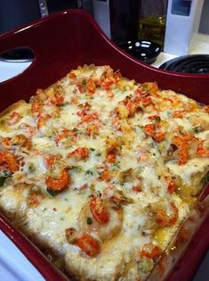 a pizza sitting on top of a red pan covered in cheese and toppings next to a computer keyboard