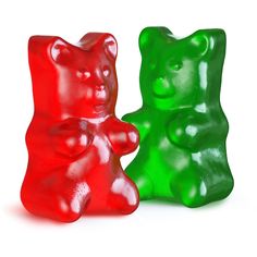 two gummy bears sitting next to each other on a white surface, one is green and the other is red