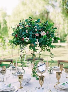 the table is set with plates, silverware and flowers in a vase on it