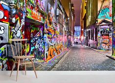 an empty street with graffiti on the walls and a chair in front of it,