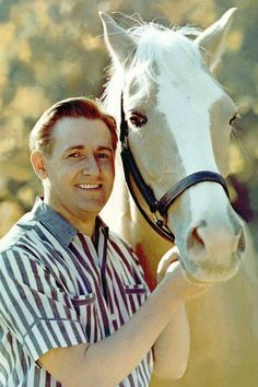 a man is holding the bridle of a horse and smiling at the camera