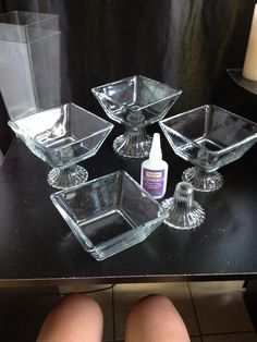 a person sitting at a table with some glass dishes and bottles on top of it