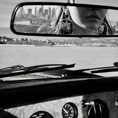 a woman's face is reflected in the rear view mirror of a car as she drives