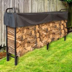 a large pile of firewood sitting next to a wooden fence