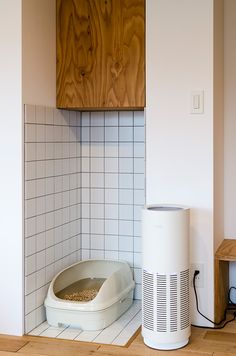 a cat litter box sitting on top of a wooden floor next to a heater