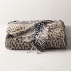 the leopard print blanket is folded on top of a white tablecloth with fringes