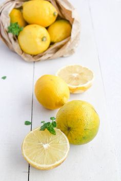 there are lemons and limes on the table next to each other in a paper bag