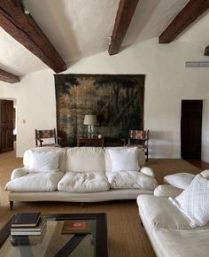 a living room filled with furniture and a large painting on the wall above it's fireplace