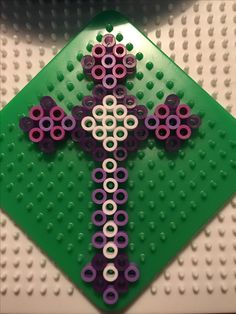 a cross made out of legos sitting on top of a green board