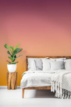 a bed with white linens and pillows in a room painted orange, pink and purple