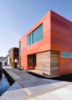 an orange house on the water next to a dock