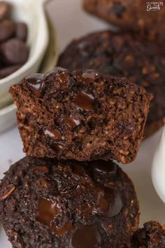 two chocolate muffins stacked on top of each other next to a bowl of chocolate chips