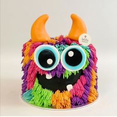 a cake decorated with multicolored icing and fake horns on it's head